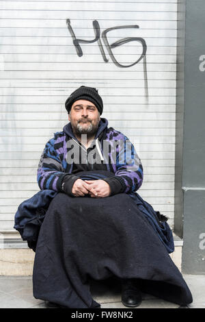 Un senzatetto si siede e attende il vano di una porta in una fredda giornata invernale e su Watling Street nella città di Londra, Regno Unito Foto Stock