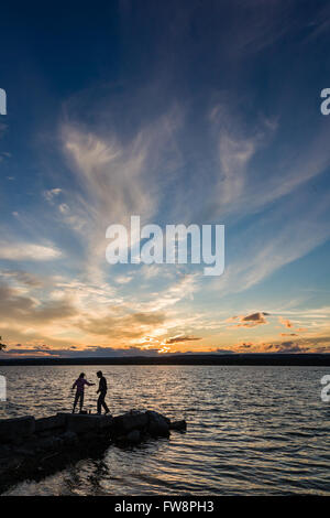 Una scena del tramonto sulla baia di Burlington con due piccole sagome di persone di pesca. Foto Stock