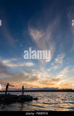 Una scena del tramonto sulla baia di Burlington con due piccole sagome di persone di pesca. Foto Stock