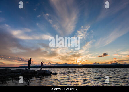 Una scena del tramonto sulla baia di Burlington con due piccole sagome di persone di pesca. Foto Stock