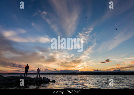 Una scena del tramonto sulla baia di Burlington con due piccole sagome di persone di pesca. Foto Stock