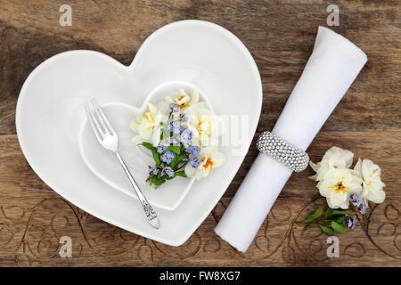 Tabella di impostazione del luogo con il bianco a forma di cuore ciotole di porcellana, argento antico, forcella fiore di primavera selezione e igienico con anello Foto Stock