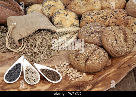 Seminate pane selezione bobina con guaine di frumento, segale grano in un sacco di Hesse con semi su un olive wood board. Foto Stock