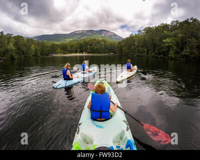 La famiglia gode di kayak sul lago Pinnacle a Table Rock State Park in Upstate Carolina del Sud. Tabella Rock è visto nel retro. Foto Stock