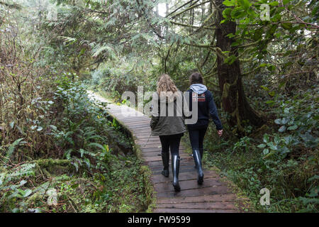 I turisti a piedi sul lungomare in una foresta, Pacific Rim National Park Riserva, Tofino, Isola di Vancouver, British Columbia, Canada Foto Stock