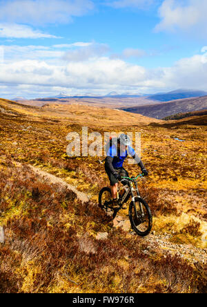 Mountain biker sulla sopra Moorland Glen Coulin in Torridon Highland scozzesi con i picchi del Fannichs nella distanza Foto Stock
