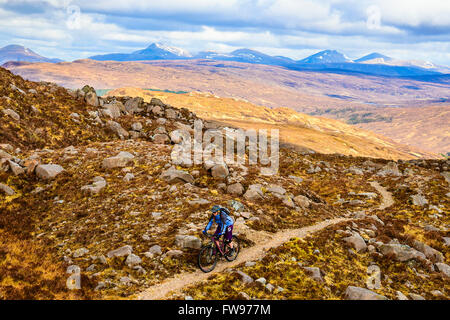 Mountain biker sulla sopra Moorland Glen Coulin in Torridon Highland scozzesi con i picchi del Fannichs nella distanza Foto Stock