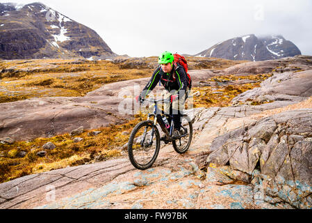 Mountain Biker iniziando la discesa da Drochaid Coire Lair per Achnashellach Highland scozzesi. Fuar Tholl sulla sinistra Foto Stock