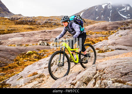 Mountain Biker iniziando la discesa da Drochaid Coire Lair per Achnashellach Highland scozzesi. Beinn Liath Mhor dietro. Foto Stock