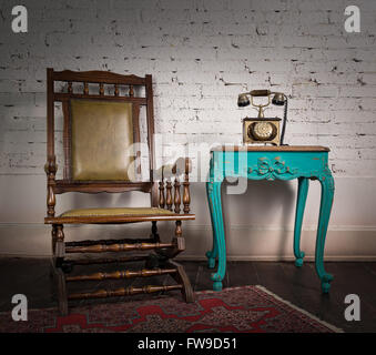 In legno sedia a dondolo, verde tabella vintage e il vecchio apparecchio telefonico Foto Stock