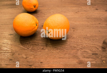 Tre arance sul tavolo di legno Foto Stock