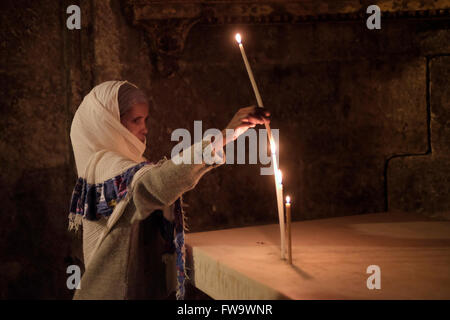 Un pellegrino cristiano dall'India accende le candele al greco Cappella di San Longino il centurione romano che trafitto Cristo E convertito al cristianesimo all'interno della Chiesa del Santo Sepolcro Città vecchia Gerusalemme Est Israele Foto Stock