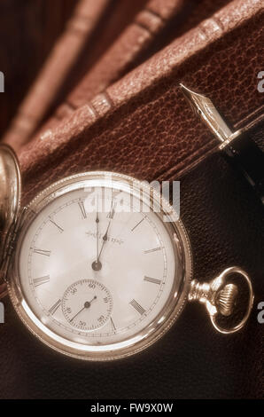 Antico orologio da tasca, penna stilografica e libri Foto Stock