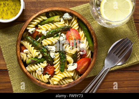 Cotta asparagi verdi, cherry pomodoro, formaggio blu e rotini insalata di pasta fredda servita nella ciotola di legno Foto Stock