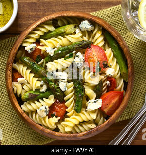 Cotta asparagi verdi, cherry pomodoro, formaggio blu e rotini insalata di pasta fredda servita nella ciotola di legno Foto Stock