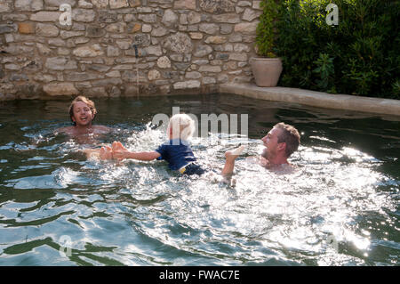 Famiglia in vacanza a giocare intorno a una piscina Foto Stock
