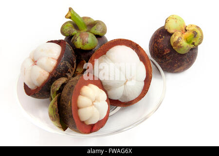 Mangosteen frutta divisa su una lastra di vetro chiara sulla isolato bianco con tracciato di ritaglio di un frutto tropicale con dolce succosa segme bianco Foto Stock