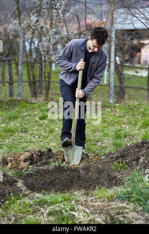 Ragazzo adolescente in vacanza a scavare nel terreno per piantare alberi Foto Stock