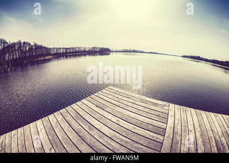 Vecchio film dai toni rétro obiettivo fisheye immagine di un molo in legno una sul lago al tramonto. Foto Stock