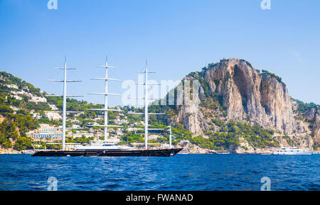 Capri, Italia - 14 agosto 2015: grande piacere yacht a vela va vicino all isola di Capri con la spiaggia di Marina Piccola su uno sfondo Foto Stock