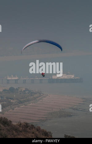 Beachy Head, Eastbourne, East Sussex, Regno Unito.2 aprile 2016.pilota Di Parapendio con Pier sullo sfondo come il mare nebbia avanza . Foto Stock