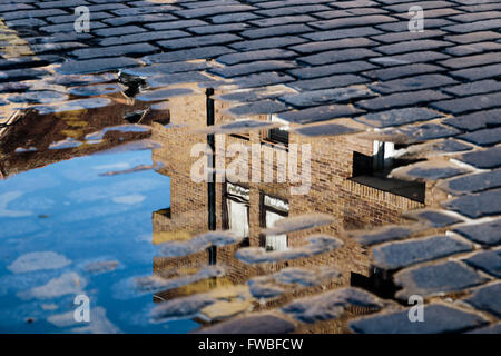 Ciottolo con la riflessione di casa nella pozza dopo la pioggia Foto Stock