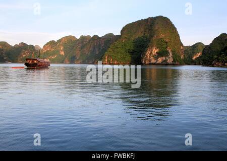 Barca indesiderata all'alba nella baia di Halong, Sito Patrimonio Mondiale dell'UNESCO, il Vietnam Asia Foto Stock