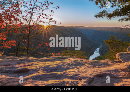 The sun dips below the mountains painting its golden light on the many textured layers of the New River Gorge in West Virginia. Foto Stock