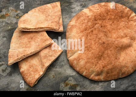 Vista dall'alto di un filone di pane pita e tre pita cunei su una tavola di ardesia. Foto Stock