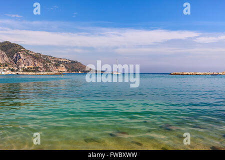 Cancellare le acque costiere del Mare Mediterraneo e piccoli yacht su sfondo di montagna in Mentone - piccola cittadina sulla Riviera Francese. Foto Stock