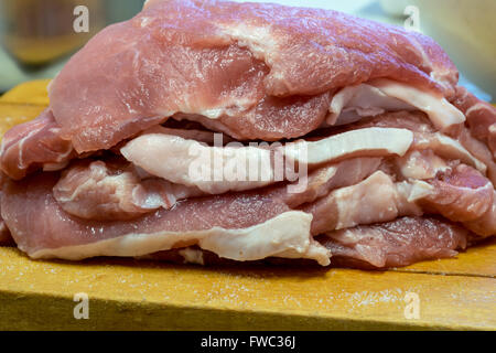 Fette di carne di maiale sul tagliere di legno Foto Stock