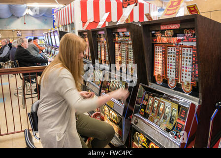 Una donna svolge un 2p slot machine in un parco di divertimenti a British seaside resort. Foto Stock