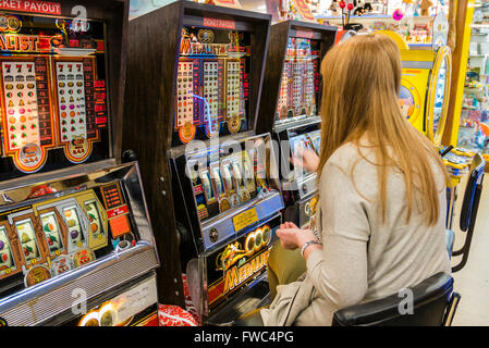 Una donna svolge un 2p slot machine in un parco di divertimenti a British seaside resort. Foto Stock