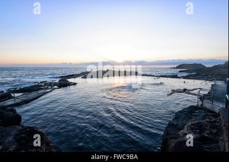 Inizio di nuotare e Sunrise over Kiama Rock Pool, Illawarra Costa, Nuovo Galles del Sud, Australia Foto Stock