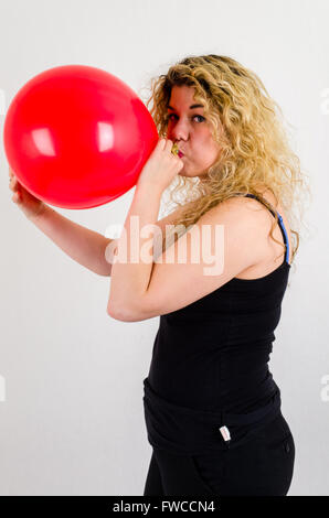 Unica femmina adulta che soffia su di medie dimensioni palloncino rosso Foto Stock