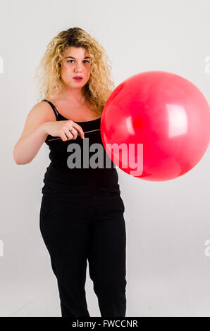 Unica femmina adulta che soffia su di medie dimensioni palloncino rosso Foto Stock