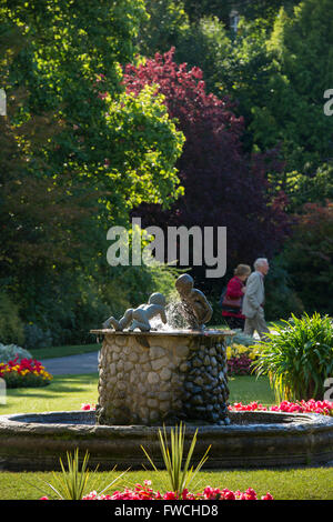 Giardini della valle, Harrogate, nello Yorkshire, Inghilterra - bella e soleggiata tranquillo parco con fontana, aiuole fiorite e 2 persone e rilassanti passeggiate. Foto Stock