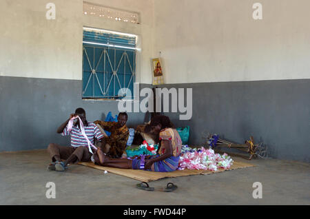 Lacekocot, distretto di Pader, Uganda. 2009. Gli uomini e le donne nella chiesa al Lacekocot sfollati interni nel campo di Pader rendere nastri e addobbi floreali per un matrimonio. La chiesa fu costruita per la trib Acholi che vivono sul campo e mettere in pratica il cristianesimo. Il gruppo di sedersi su un coloratissimo tappeto sul pavimento di cemento. Foto Stock