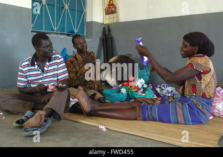 Lacekocot, distretto di Pader, Uganda. 2009. Gli uomini e le donne nella chiesa al Lacekocot sfollati interni nel campo di Pader rendere nastri e addobbi floreali per un matrimonio. La chiesa fu costruita per la trib Acholi che vivono sul campo e mettere in pratica il cristianesimo. Il gruppo di sedersi su un coloratissimo tappeto sul pavimento di cemento. Foto Stock