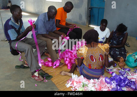 Lacekocot, distretto di Pader, Uganda. 2009. Gli uomini e le donne nella chiesa al Lacekocot sfollati interni nel campo di Pader rendere nastri e addobbi floreali per un matrimonio. La chiesa fu costruita per la trib Acholi che vivono sul campo e mettere in pratica il cristianesimo. Il gruppo di sedersi su un coloratissimo tappeto sul pavimento di cemento. Foto Stock