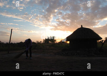 Lacekocot, distretto di Pader, Uganda. 2009. La sun red imposta oltre il paesaggio di capanne di fango e palme al Lacekocot sfollati interni nel campo di Pader, Uganda settentrionale. Foto Stock