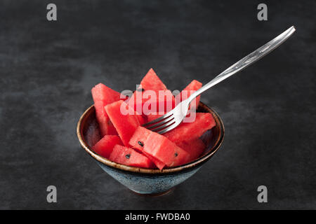 Fette di anguria in ceeramic ciotola con forcella sul buio grungy sfondo con copia spazio. Profondità di campo. Foto Stock