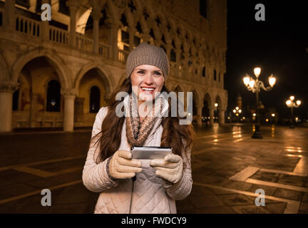 Passeggiata serale a Venezia vi portano in un altro mondo. Felice giovane donna azienda turistica smartphone e guardando nel dista Foto Stock