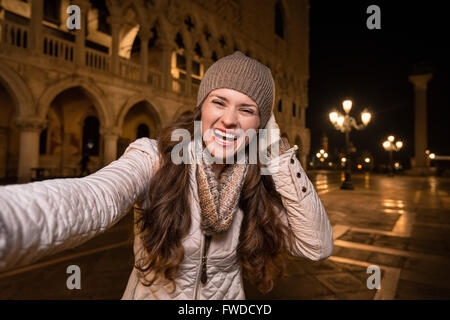 Passeggiata serale a Venezia vi portano in un altro mondo. Felice giovane donna turistica prendendo selfie su Piazza San Marco vicino Dogi Foto Stock