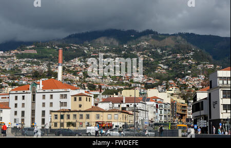 Vista verso monte dalla passeggiata sul lungomare di Funchal, Madeira, Portogallo. Con tempestoso, nuvoloso Meteo montagna Foto Stock