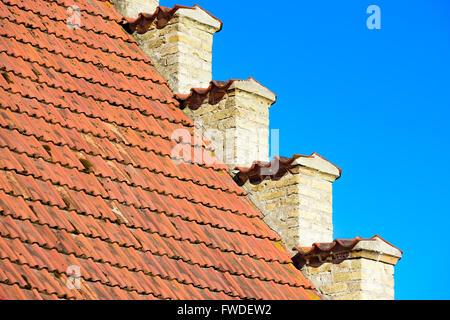 Incantevoli dettagli architettonici di una vecchia casa di mattoni dove la facciata di colore giallo incontra il tetto di tegole rosse e. Foto Stock