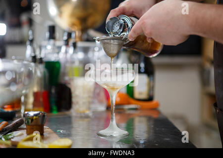 Barista coocks cocktail dietro un banco di bar Foto Stock