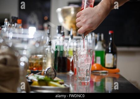 Barista coocks cocktail dietro un banco di bar Foto Stock