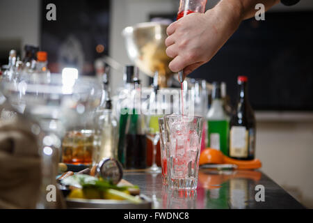 Barista coocks cocktail dietro un banco di bar Foto Stock