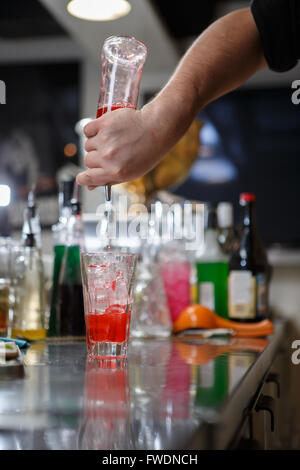 Barista coocks cocktail dietro un banco di bar Foto Stock